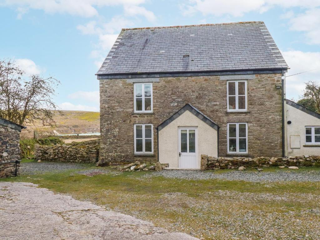 an old stone house with a white door at Poldue House in Camelford