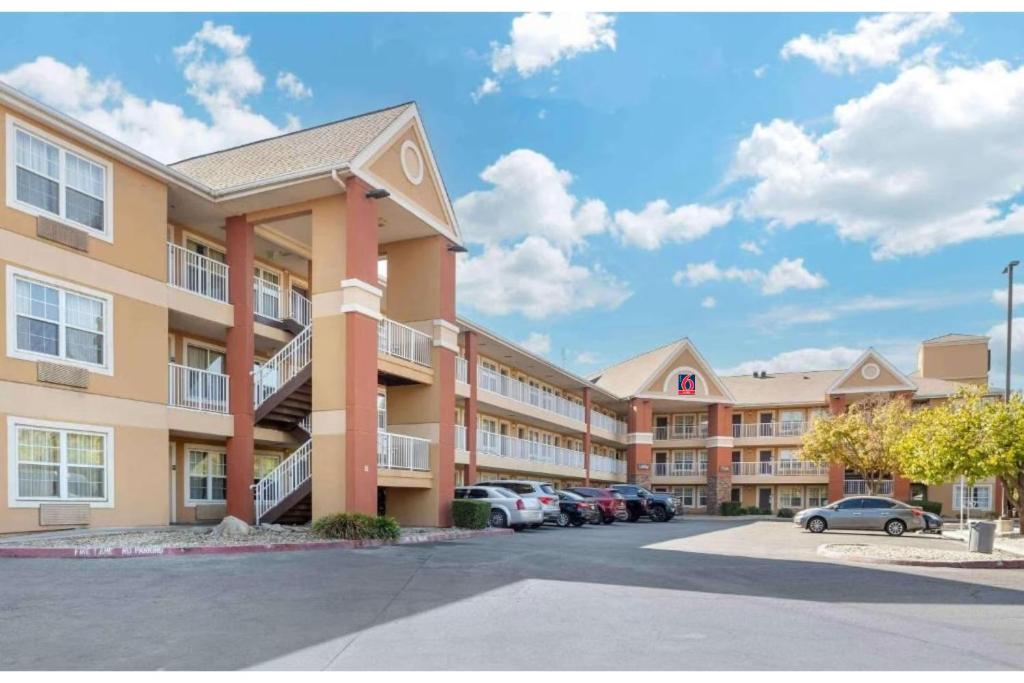 a large apartment building with cars parked in a parking lot at Studio 6 Suites Fresno North CA in Fresno