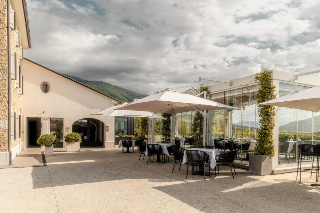 a patio with tables and chairs and umbrellas at Locanda MaMaGiò in Valdobbiadene
