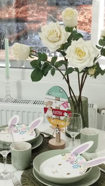 ein Tisch mit weißen Tellern und eine Vase mit Rosen in der Unterkunft AMBER Studio in Craiova