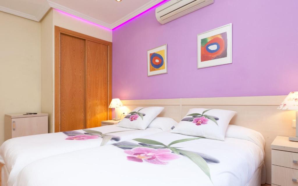 ein Schlafzimmer mit lila Wänden und einem Bett mit Blumen darauf in der Unterkunft Luz Madrid Rooms in Madrid