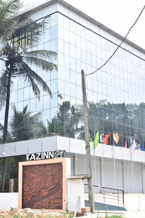 a tall building with a sign in front of it at Tazinn in Wayanad