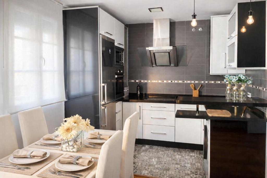 a kitchen with a table with white cabinets and a black counter at ático con terraza- solarium in Écija