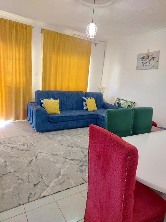 a living room with a blue couch and two chairs at JJHomes in Eldoret