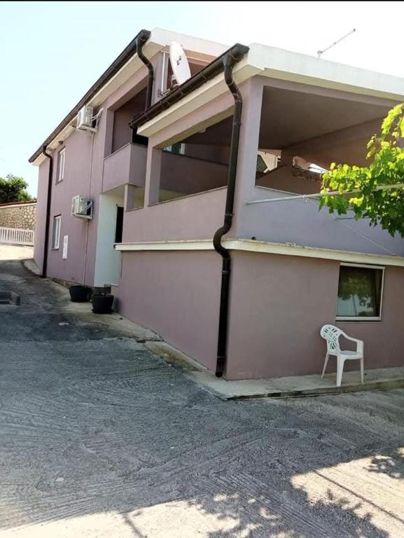 a white chair sitting outside of a pink building at Apartmani Marija Rtina in Rtina
