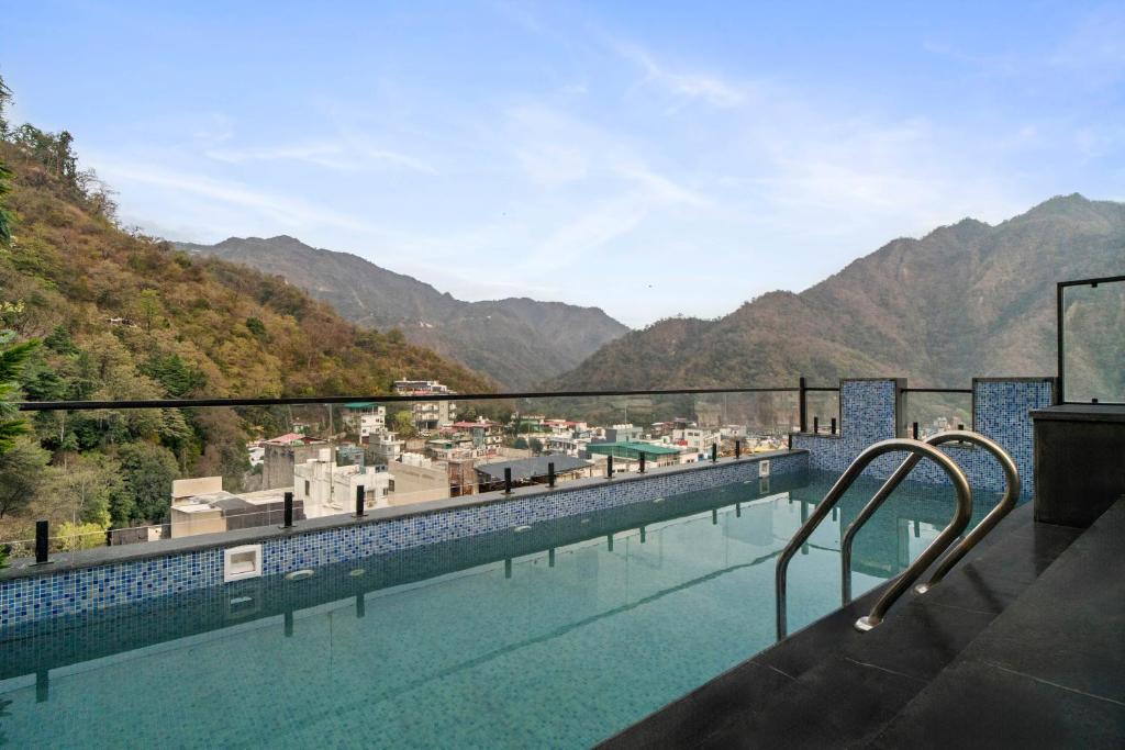 a swimming pool with mountains in the background at Country Inn Smart Stays, Rishikesh at Tapovan in Rishīkesh