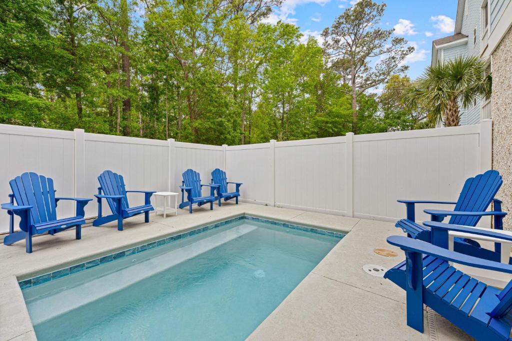 a pool with blue chairs next to a fence at 200 Olive Shell Court in Hilton Head Island