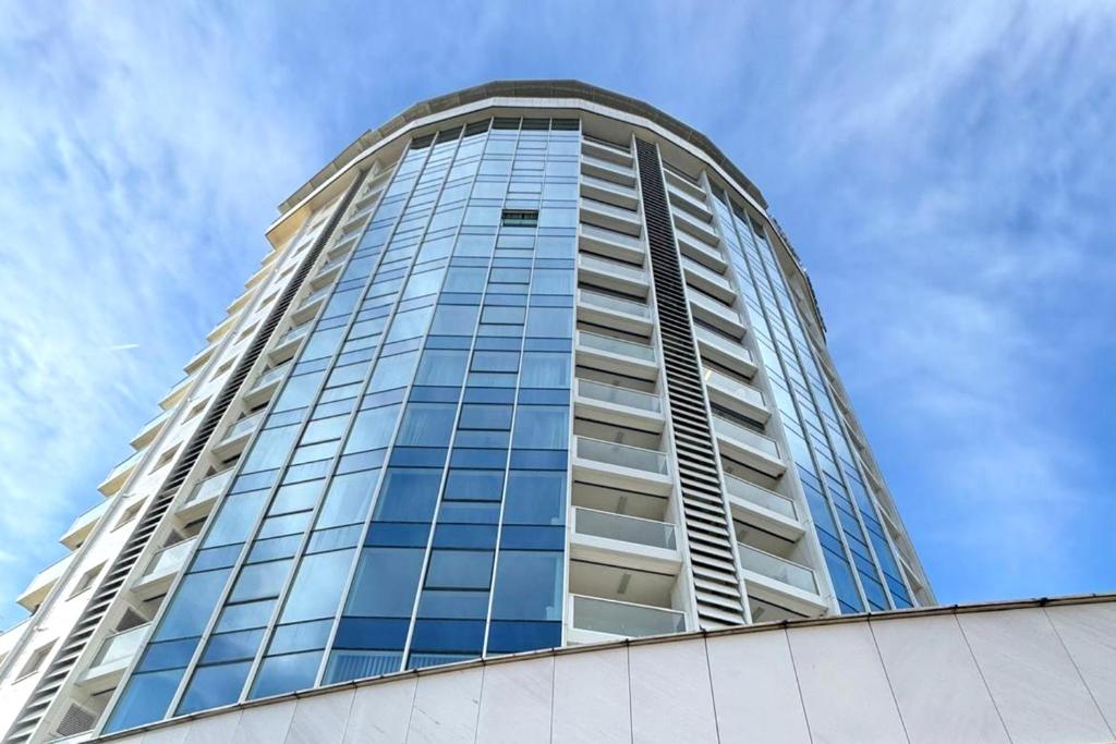 a tall glass building with a blue sky in the background at Tre Canne Vista in Budva