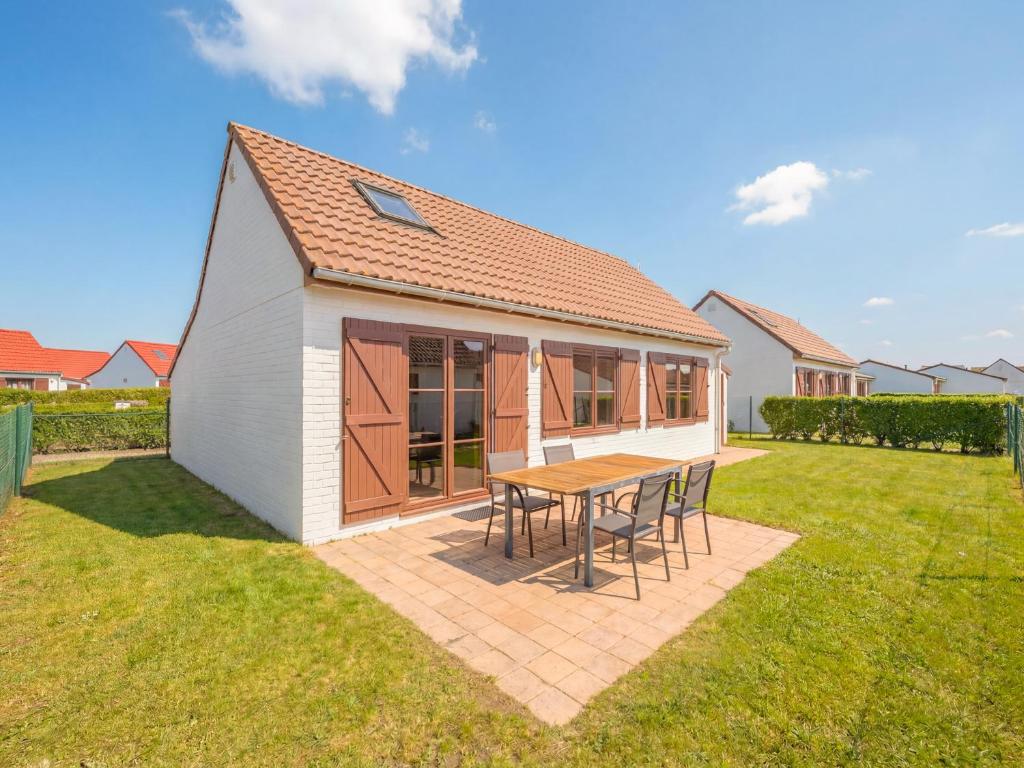 ein kleines Haus mit Tisch und Stühlen in einem Hof in der Unterkunft Zeepark Haerendycke in Wenduine