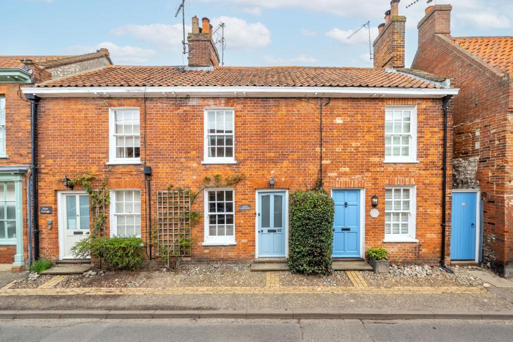 a brick house with blue doors on a street at Petts Cottage in Burnham Market