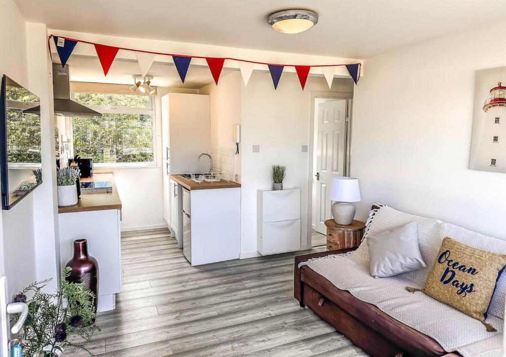 a living room with a couch and a kitchen at Seaside Serenity at Ocean Days in Brading