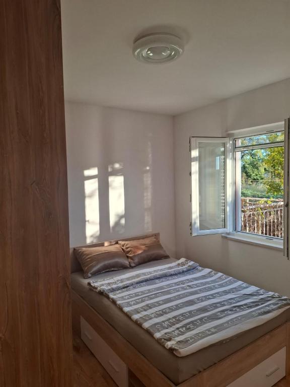 a bed in a room with a window at Apartman Mirjana in Mlini