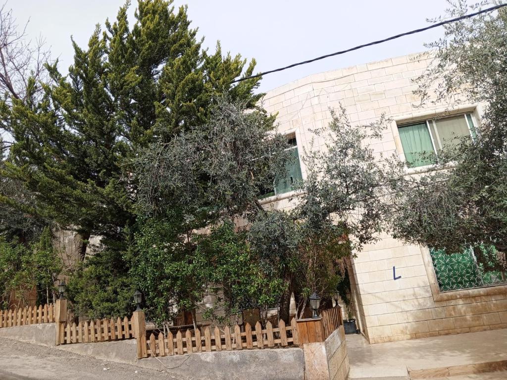 a fence in front of a house with trees at Flowers in Jerash