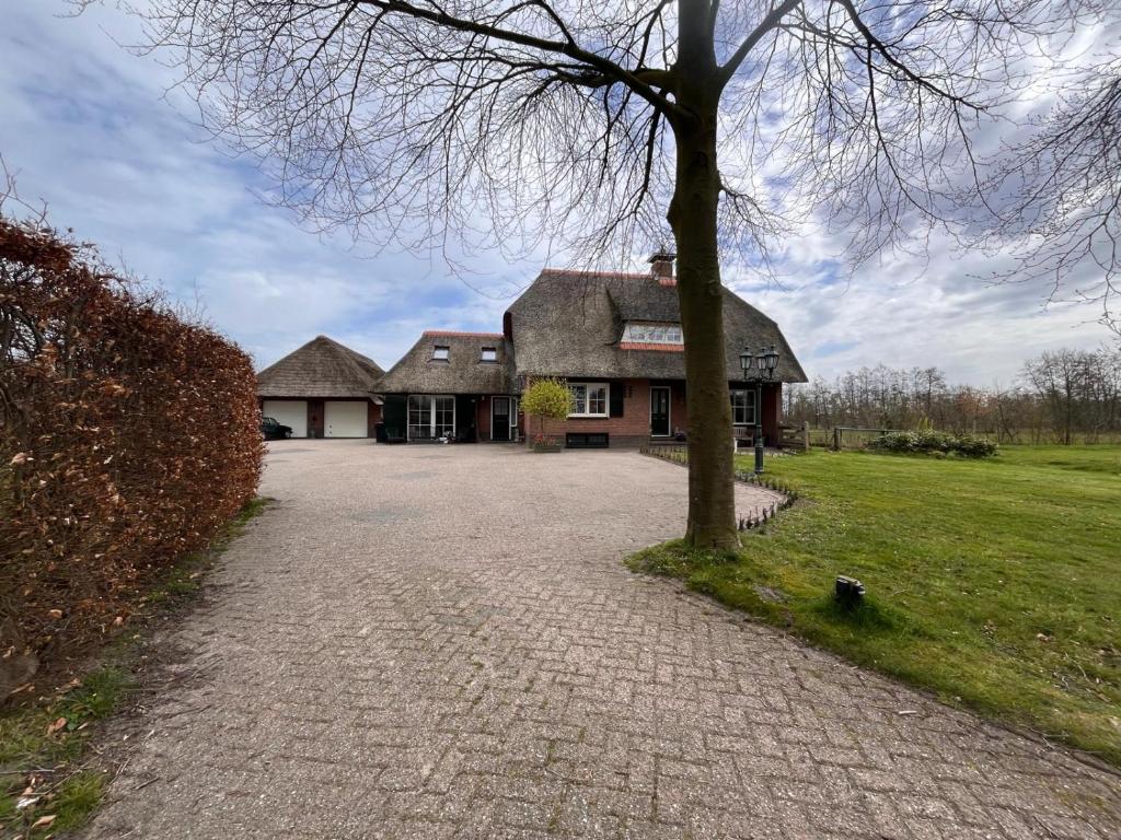 a large house with a tree in front of it at It Jachtfjild in Het Jachtveld