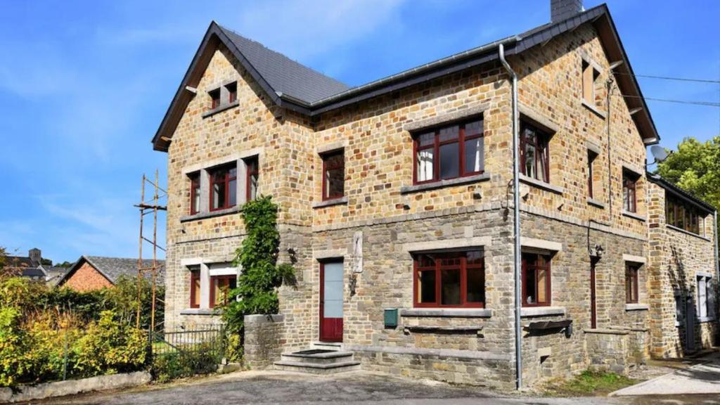 a brick house with red windows and a black roof at Vakantie & wellness Erezee in Érezée