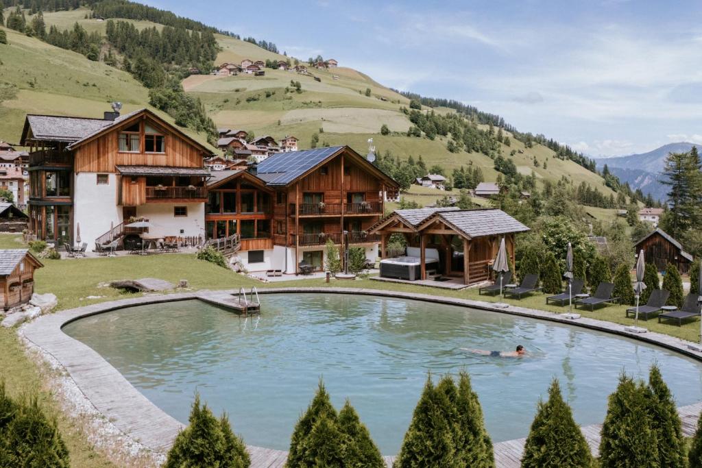 a person swimming in a pool in front of a house at Chalet Mornà in San Martino in Badia