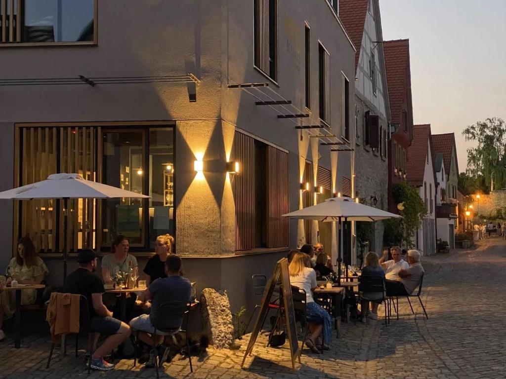 Eine Gruppe von Menschen sitzt an Tischen vor einem Restaurant in der Unterkunft Hotel-Weingut Bernard in Sulzfeld am Main