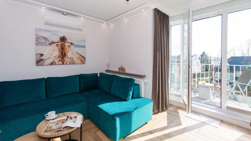 a living room with a blue couch and a large window at Apartament 19A - Villa Neptun in Gdańsk