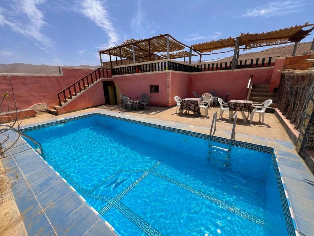 a pool with a table and chairs and a house at Riad Bouchra in Tinerhir