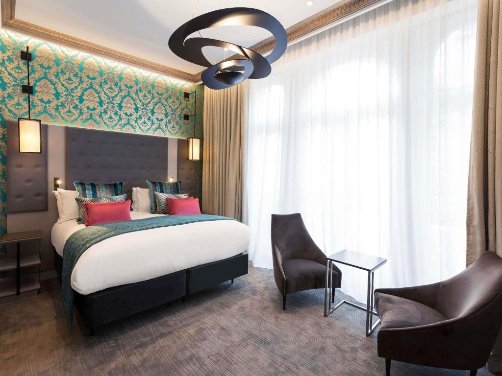 a bedroom with a large bed and a chandelier at Mercure London Hyde Park Hotel in London