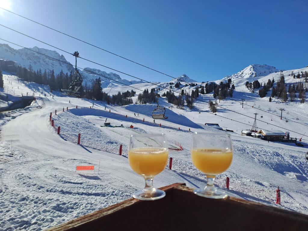 two glasses of orange juice sitting on a table next to a ski slope at MON SKI A LA PLAGNE - PLAGNE BELLECOTE Résidence 3000 in Plagne Bellecote
