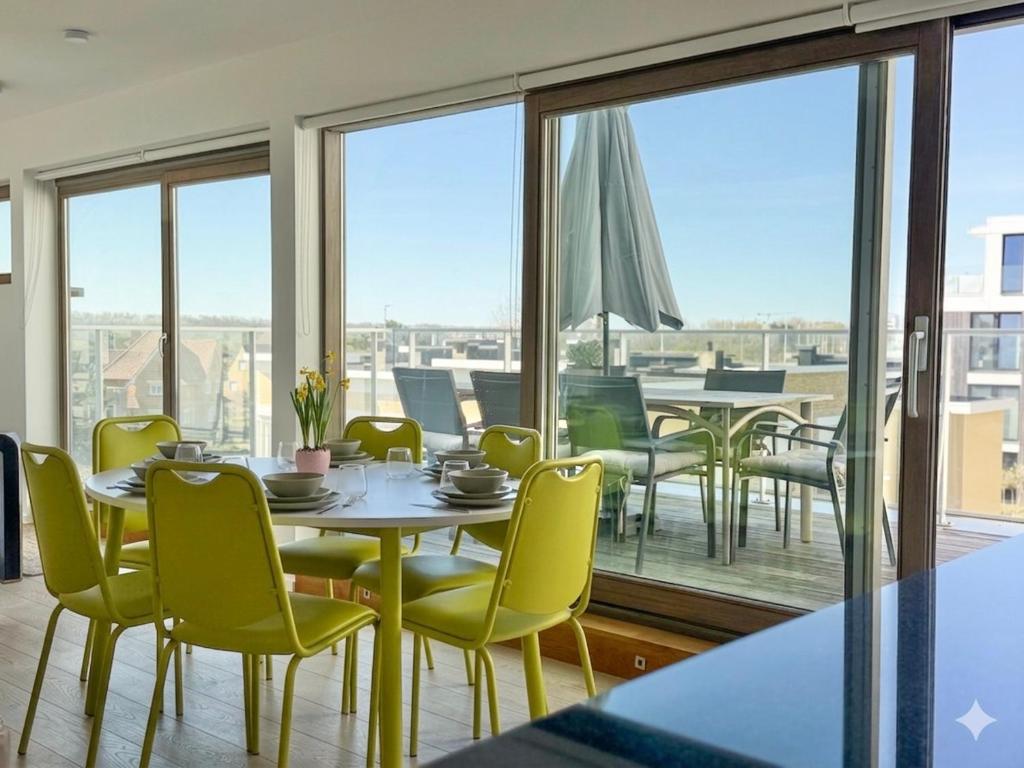 a dining room with a table and chairs and windows at Camelia 0202 - With Swimming Pool in Koksijde