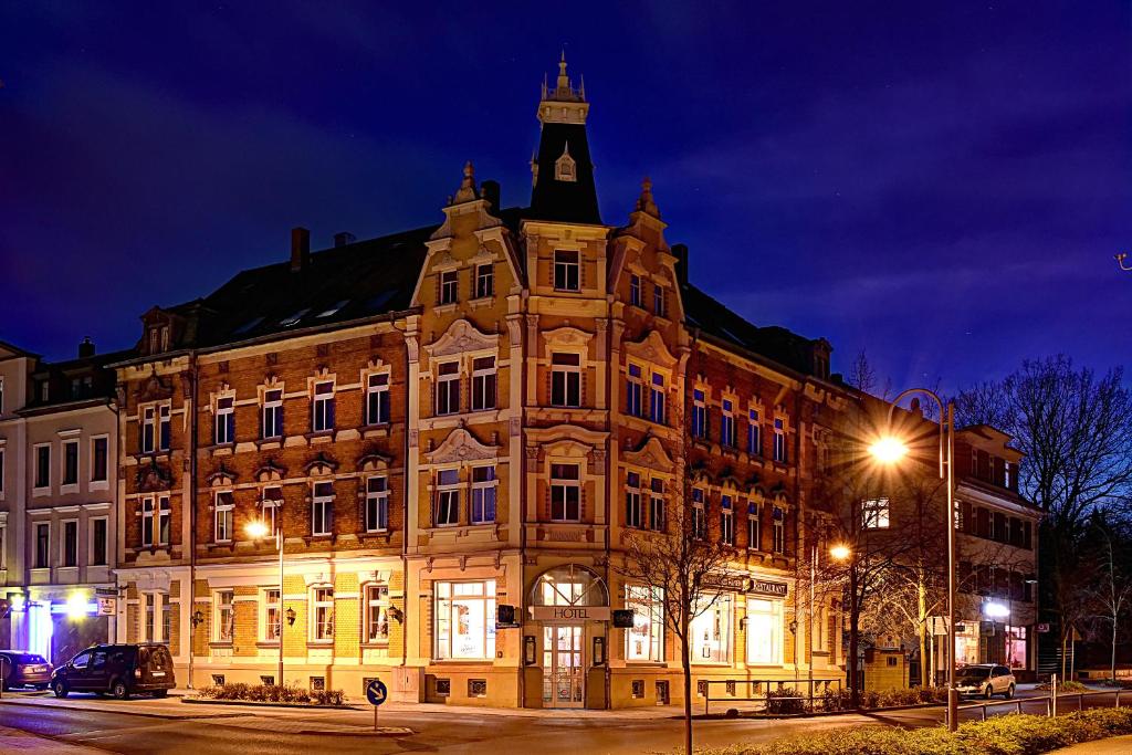 a large building with a clock tower on top at night at Hotel Drei Rosen in Borna