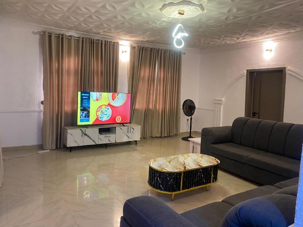 a living room with a couch and a flat screen tv at KFP Serene and Modern 2BR Flat , IBD in Ibadan