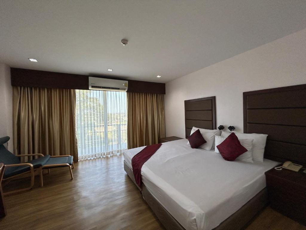 a hotel room with a bed and a large window at Teak Garden Resort, Chiang Rai in Chiang Rai