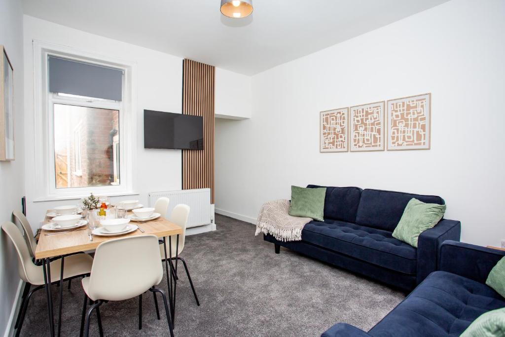 a living room with a blue couch and a table at Vacant Nests The Ropery 4BR Seafront in Seaham