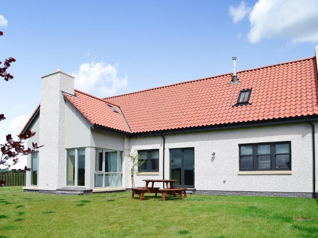 a white house with a red roof and a picnic table at Veleta in Grange