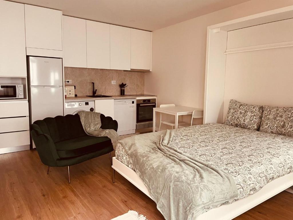 a bedroom with a bed and a chair and a kitchen at Casa da Avo Ilda - Near the Sea in Matosinhos