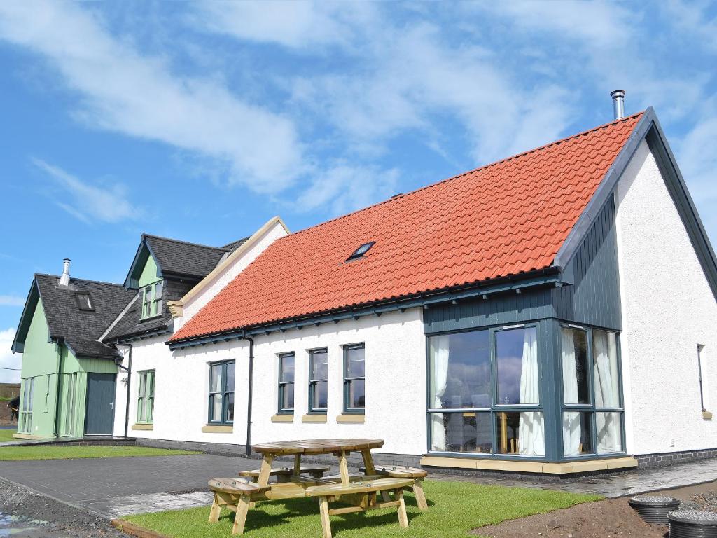 an orange roofed house with a picnic table in front at Strathspey in Grange
