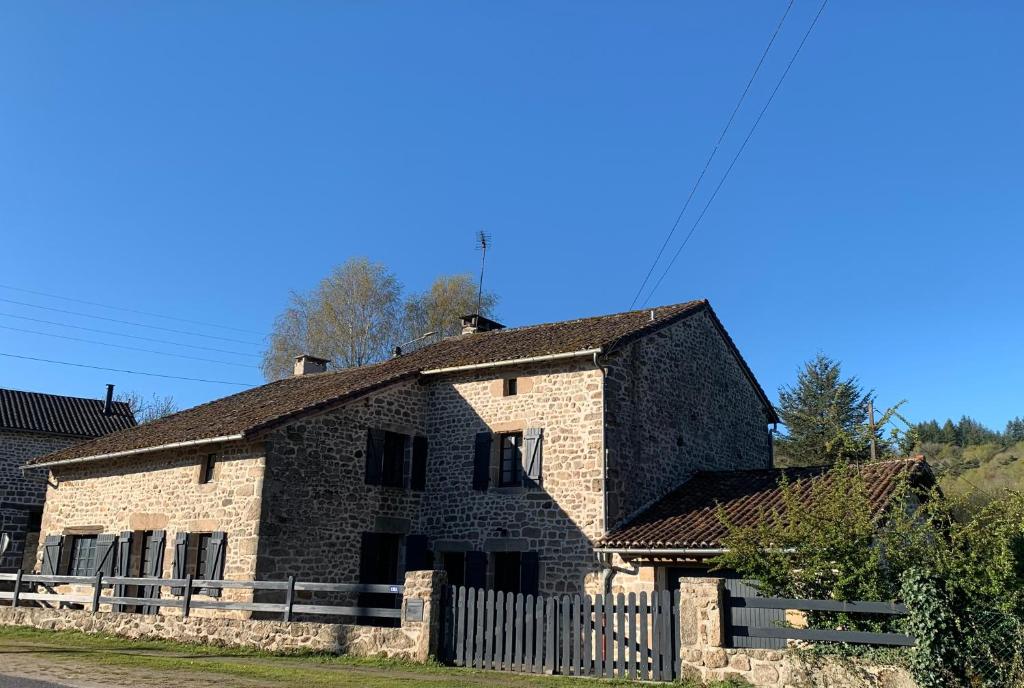 an old stone house with a fence in front of it at Vacances au Lac de Saint-Pardoux in Compreignac