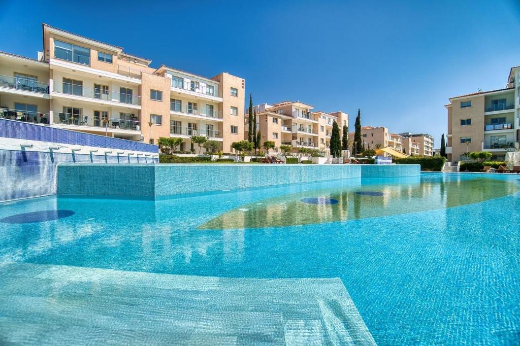 a large blue swimming pool with buildings in the background at Elysia Park Star in Paphos
