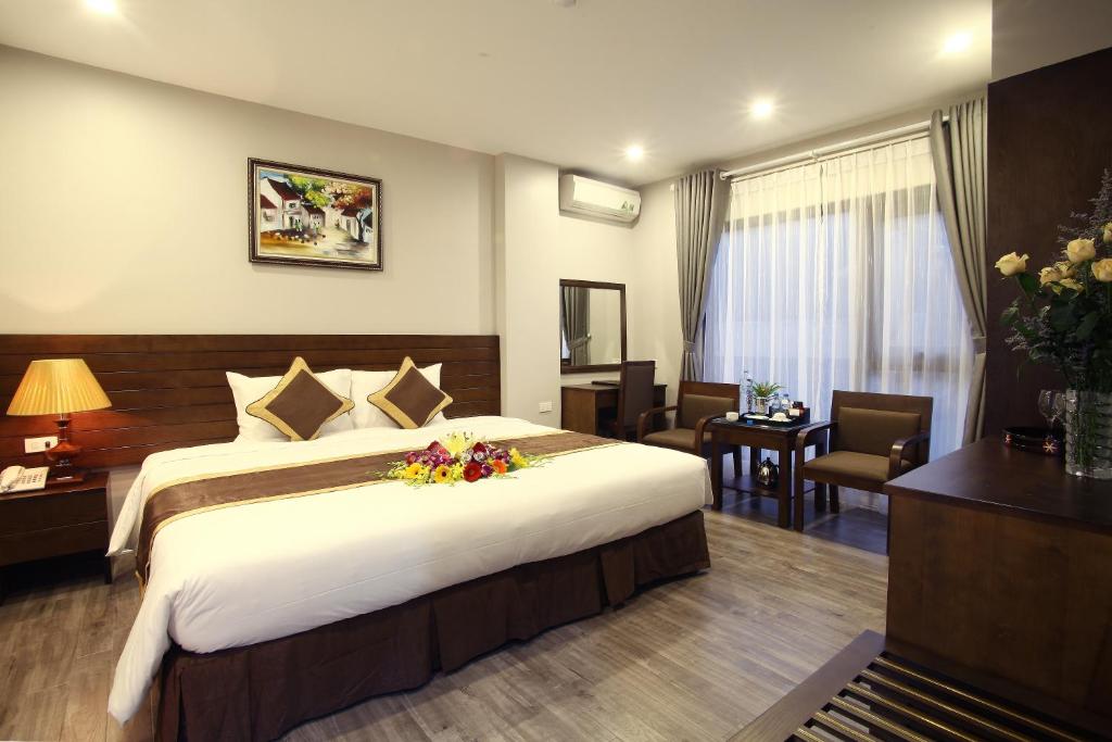 a hotel room with a large bed with flowers on it at Blue Pearl West Hotel in Hanoi