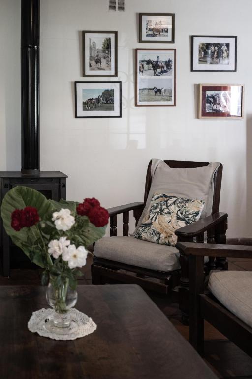 a living room with a chair and a vase of flowers on a table at La Cuadra - Puesto de Campo Argentino in Lobos