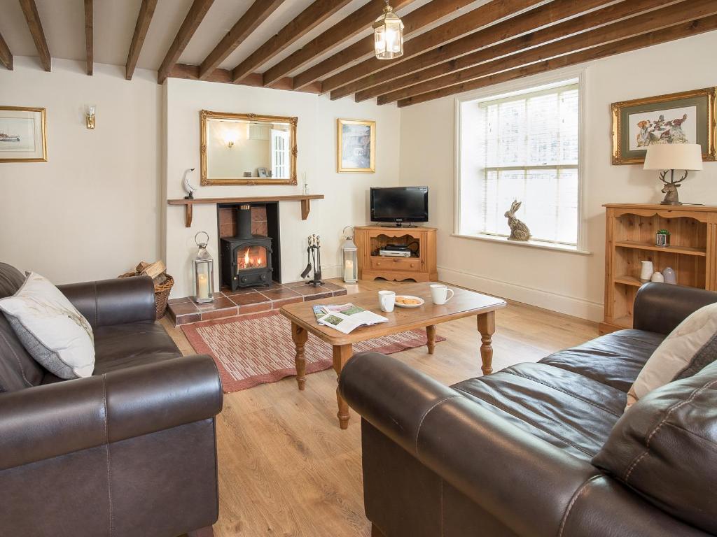 a living room with leather furniture and a fireplace at Hudson Cottage - Uk38152 in Newton