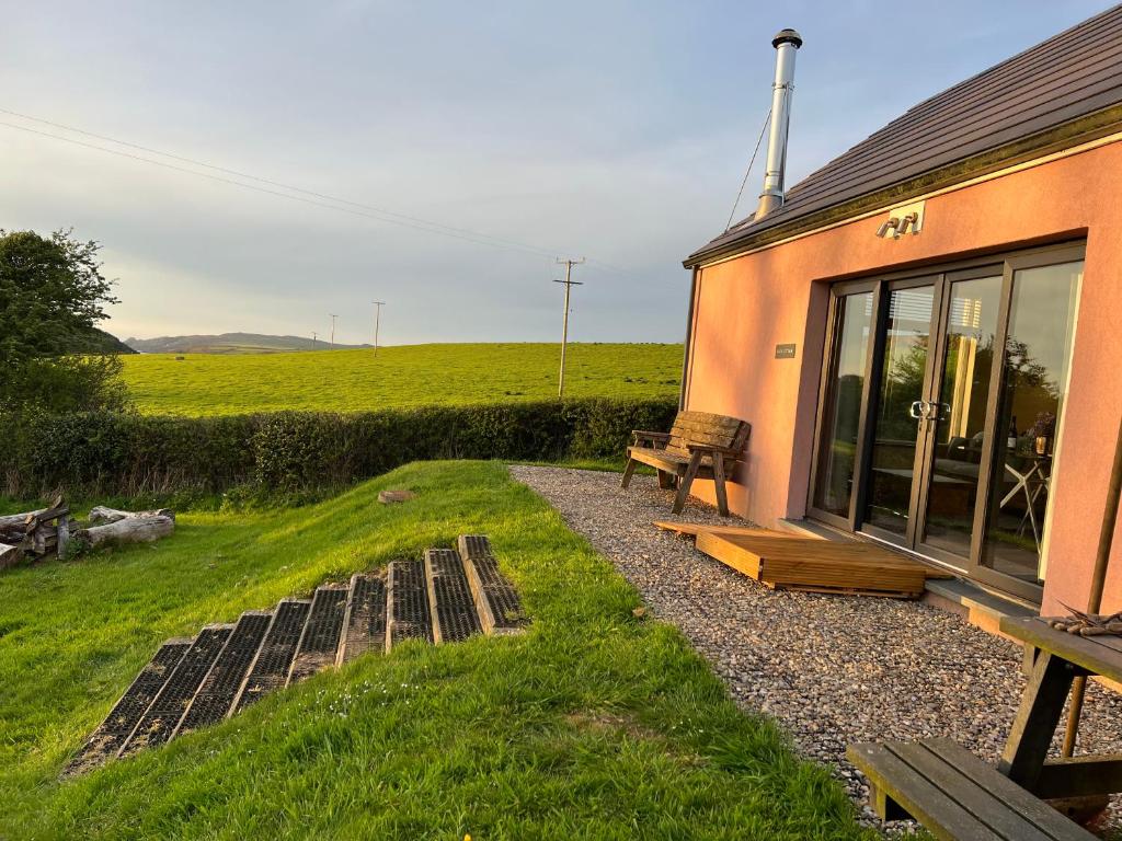 a bench sitting outside of a building with a field at Loom Cottage, Preseli Venture in Haverfordwest