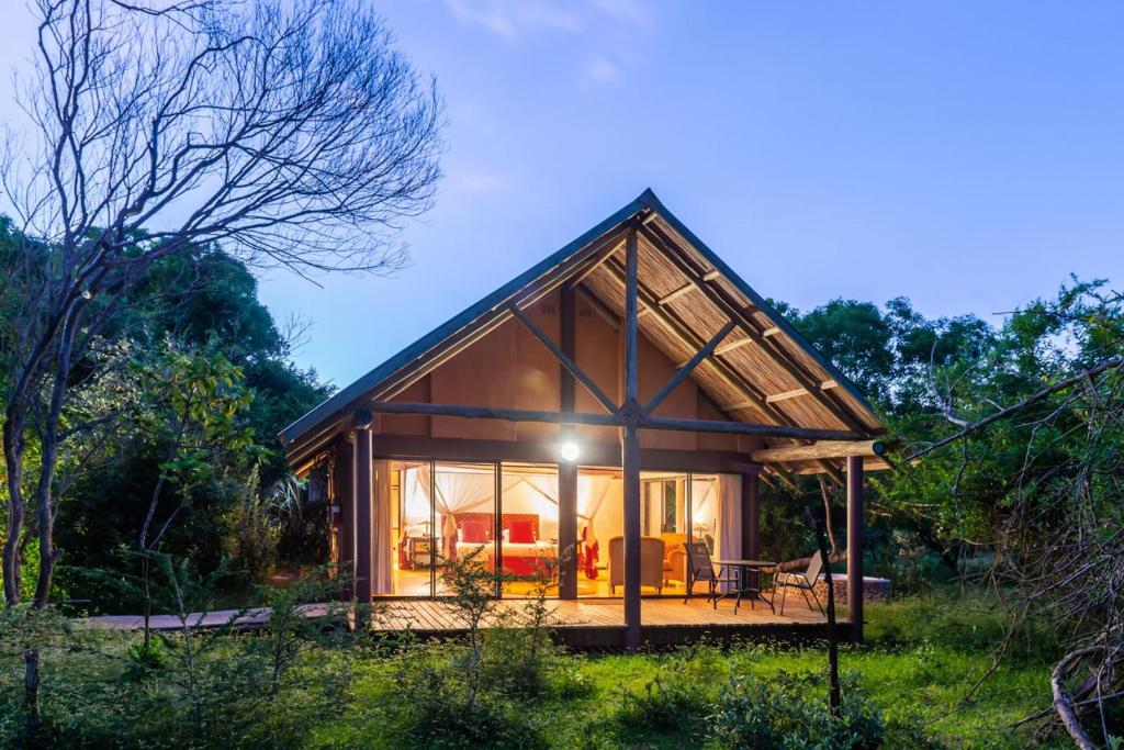 a small cabin in the woods with a large window at Leopard Walk Lodge in Hluhluwe
