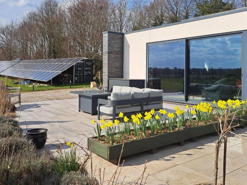 a patio with flowers and a couch and a table at Park Barn in Whittington