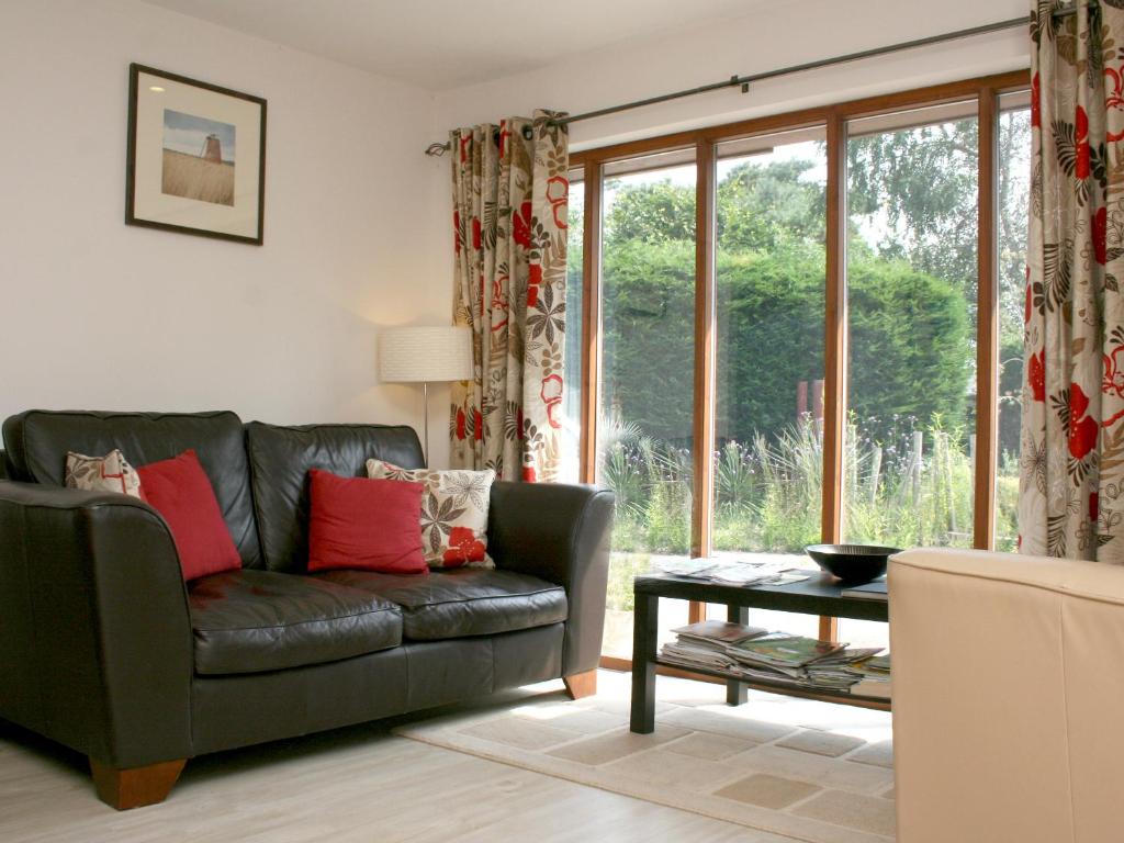 a living room with a leather couch and a table at Sandhole Barn in Snodland