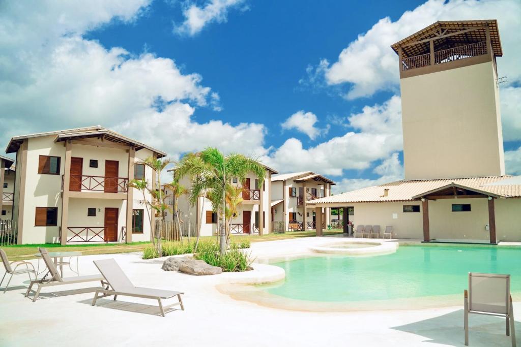 a resort with a swimming pool and a tower at Chalé Dunas de Amaro, completo e aconchegante in Santo Amaro