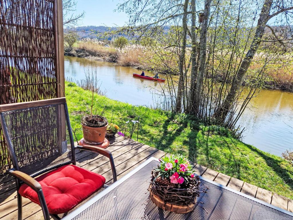 a porch with a chair and flowers and a river at Holiday Home Tiny Haus am Altmühlufer by Interhome in Beilngries