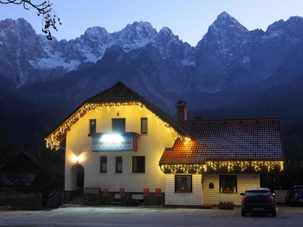 a building with christmas lights on it in front of mountains at Apartments and Rooms Jozica in Kranjska Gora