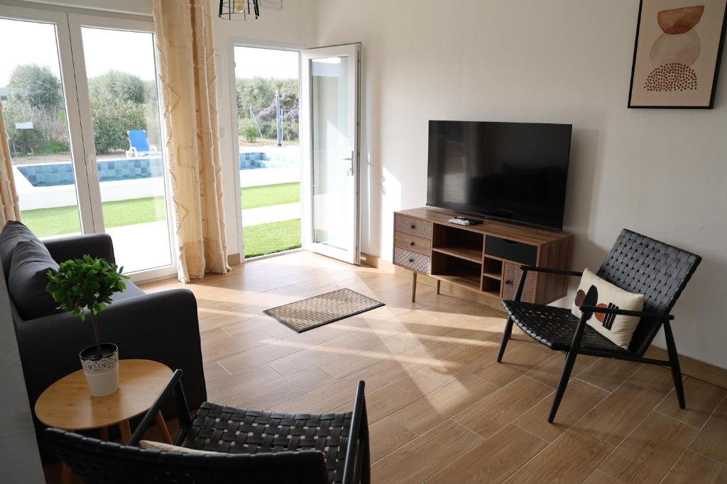 a living room with a television and chairs and a table at Olivale Villas in Campo Maior