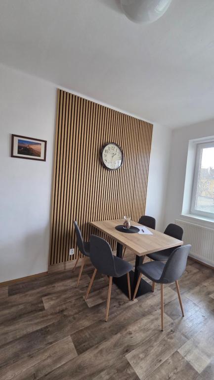 a dining room with a table and chairs and a clock at Apartmán Eliašova 2 in Česká Lípa
