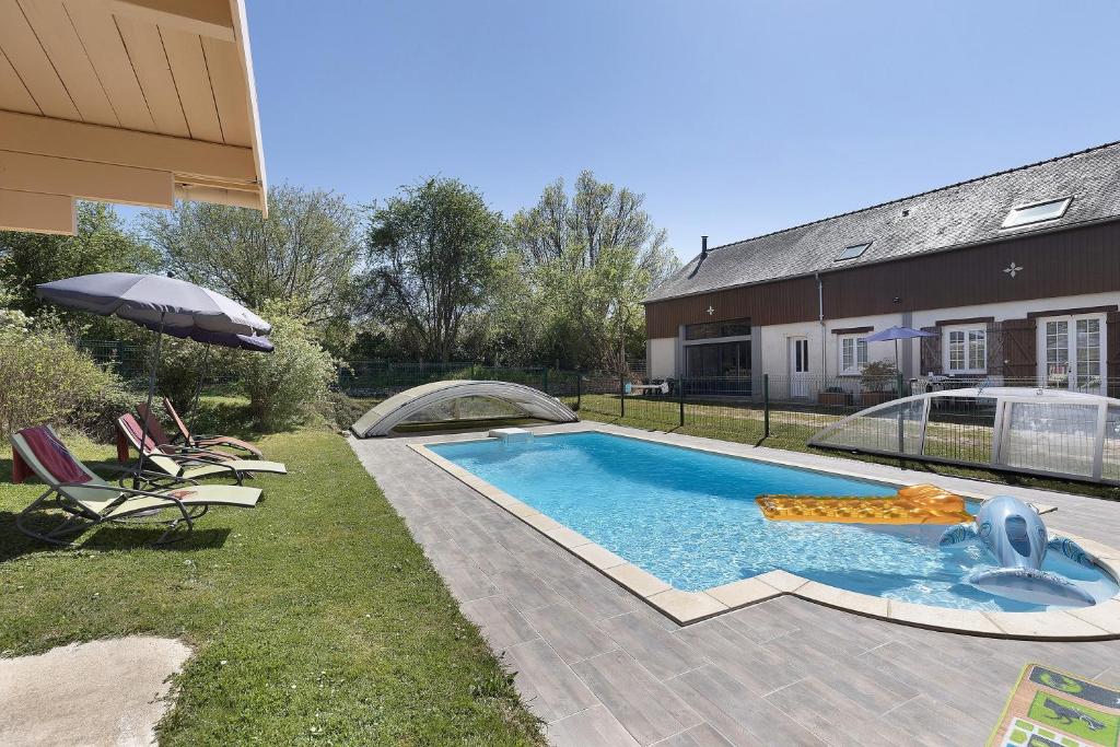 a swimming pool in a yard next to a house at Gîte Bricabroc 2 adultes 2 enfants in Noyant