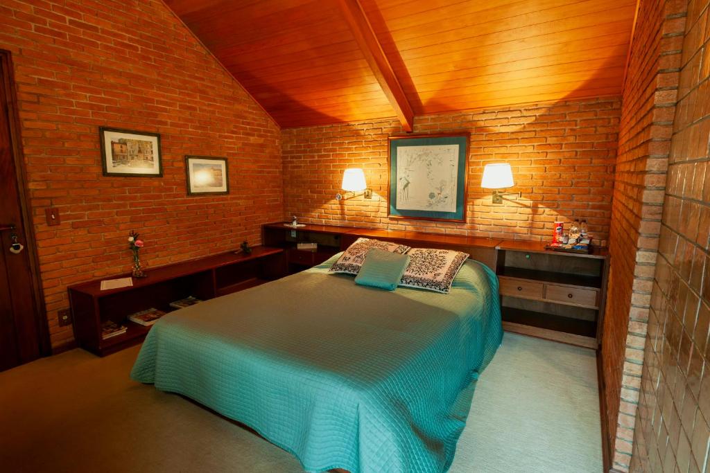 a bedroom with a bed and a brick wall at Estalagem Entardecer da Serra in Monte Verde