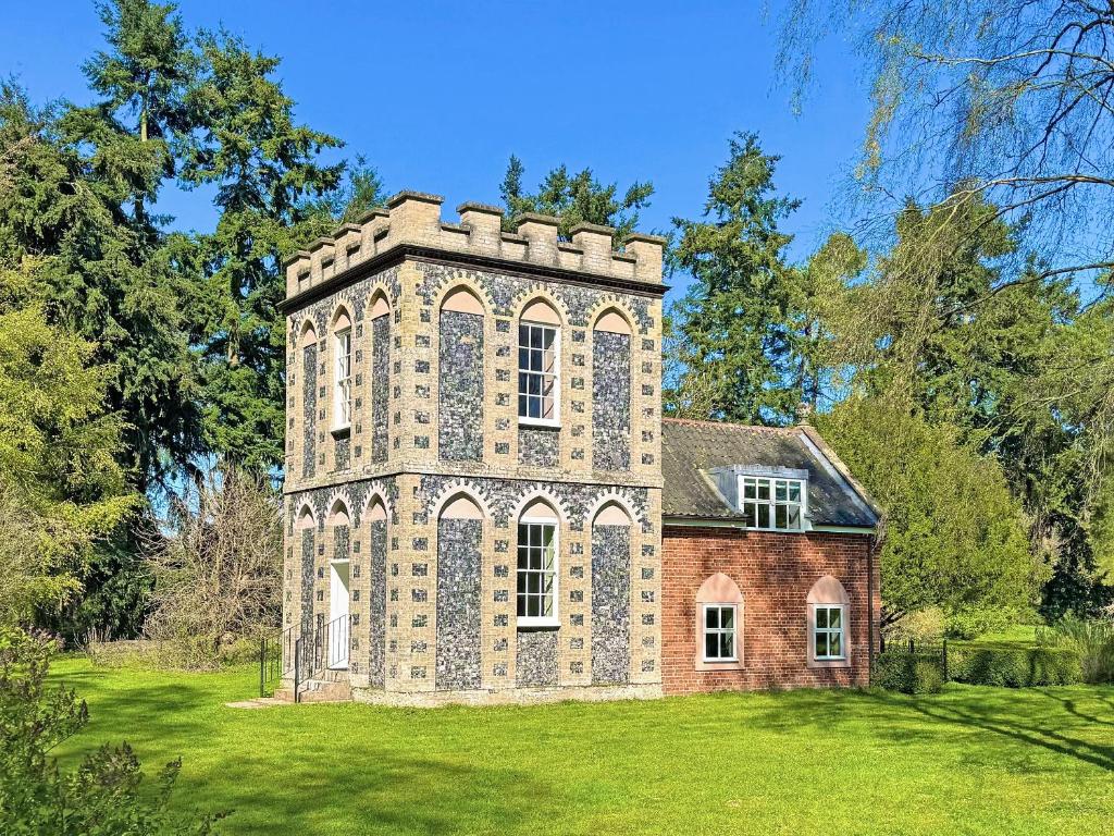 an old brick house with a tower on a lawn at Falconer's Lodge in Didlington